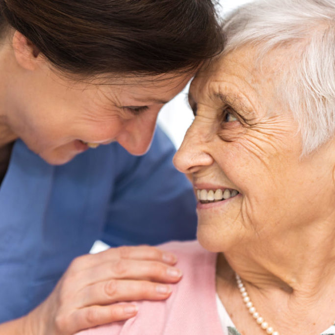 Nursing home - happy senior woman and home caregiver