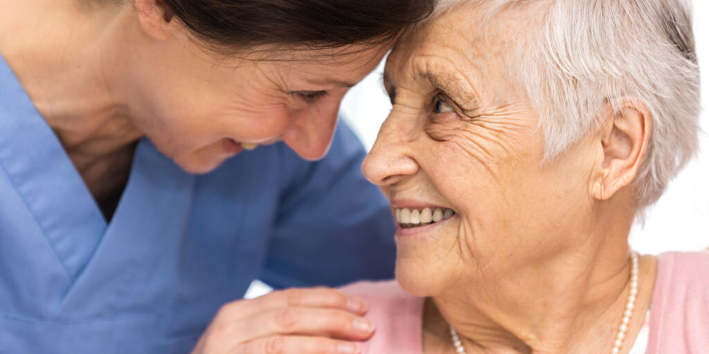 Nursing home - happy senior woman and home caregiver